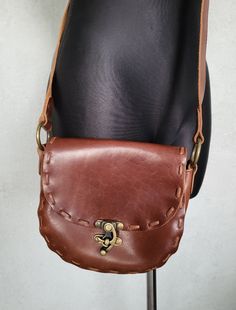 "Women`s rustic crossbody boho bag. Vintage cognac brown leather crossbody bag, crafted shoulder bag. Boho style accessory by Zara. Flap bag with frontal metal (golden tone) closure. Without lining.  Adjustable shoulder strap.  brand: ZARA ( ZARA is a Spanish multi-national retail clothing chain.) condition: normal vintage. Without serious damages. Has some slight streaks on the surface, bottom some darker spot - looks natural.  Closure works well. measurements: height 18 cm / 7\" in width 19 cm Brown Crossbody Shoulder Bag With Brass Hardware, Rustic Brown Bags With Leather Handles, Handmade Brown Bags For Festival, Rustic Brown Bags With Leather Lining, Rustic Brown Bag For Everyday Use, Rustic Brown Leather Bag, Brown Saddle Shoulder Bag With Brass Hardware, Bohemian Brown Satchel With Adjustable Strap, Rustic Brown Shoulder Bag With Leather Handles