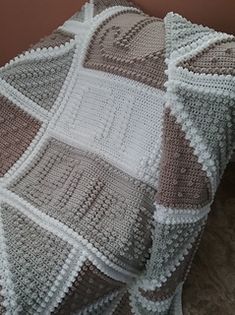 a crocheted blanket sitting on top of a bed next to a brown wall