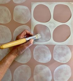 a person using a brush to paint circles on a wall