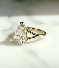 a pear shaped diamond ring sitting on top of a table