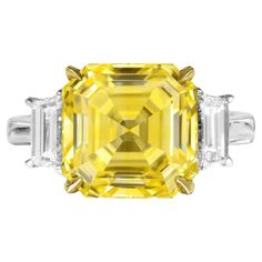 This exquisite ring is centered around a magnificent 3.08 ct Asscher-cut diamond, a true masterpiece of design and craftsmanship. The diamond, certified by the Gemological Institute of America (GIA), boasts a Fancy Yellow color, radiating a rich, vibrant hue that is both captivating and rare. Its VVS2 clarity rating ensures that it is nearly flawless, with very, very slight inclusions that are difficult to detect even under close inspection. The Asscher cut of the diamond is a testament to its refined elegance, featuring a unique step-cut faceting that creates a hall-of-mirrors effect. This distinctive cut, combined with the diamond's exceptional color and clarity, produces a mesmerizing depth and brilliance. Setting this extraordinary diamond is a sophisticated band crafted in both 18k ye Colored Engagement Ring, Asscher Cut Diamond Engagement Ring, Harry Winston Diamond, Asscher Cut Engagement Rings, Canary Diamond, Yellow Diamond Ring, Yellow Diamonds Engagement, Asscher Cut Diamond, Yellow Diamond Rings