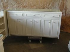 a white cabinet sitting in the middle of a room next to some shelves and drawers