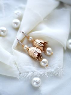 some pearls are laying on top of a piece of white fabric with gold leaves and beads