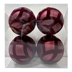 three red glass balls sitting on top of each other in front of a clear box