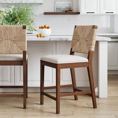 two chairs sitting in front of a kitchen counter with fruit on the table next to it