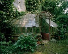 an old greenhouse is surrounded by greenery and trees