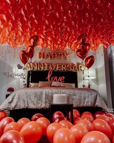 balloons are floating in the air above a bed with a happy anniversary sign on it