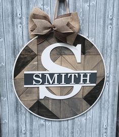 a wooden sign with a bow on it that says smith and is hanging on the side of a building