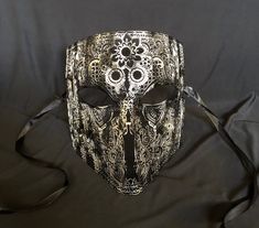 This men's Venetian masquerade mask is made of a lightweight metal and is hand painted. The abstract paint job gives the mask a unique look. Stand out at your next costume or masquerade party with this awesome mask! Mask has some flexibility and come with black silk ribbon ties attached. Mask size 6"W x 7"H. Mask color silver/black. By Essance Masquerade. Gothic Full Face Mask For Masquerade, Gothic Full Face Masquerade Masks, Gothic Full Face Masks And Prosthetics For Masquerade, Steampunk Black Masquerade Mask For Halloween, Steampunk Masks And Prosthetics For Carnival Festival, Gothic Masquerade Mask For Carnival Festival, Black Full Face Carnival Masks, Gothic Eye Mask For Carnival, Steampunk Eye Masquerade Mask For Costume