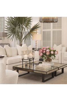 a living room filled with white furniture and lots of flowers on top of a coffee table