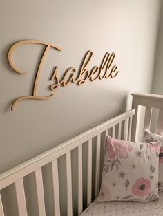 a baby's crib with a name sign above the crib and pillows