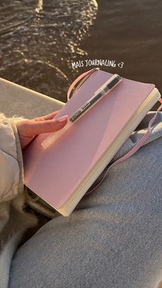 a person sitting on a boat with a notebook and pen in their lap