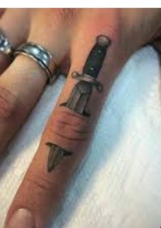 a person with a knife tattoo on their hand