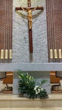 a cross with flowers and candles in front of it