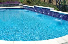 an empty swimming pool with blue tiles on the sides and water running down the side