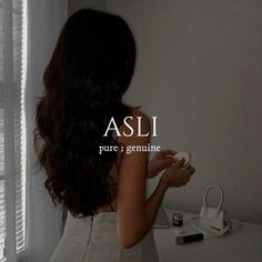 a woman standing in front of a window with the words asli on her back