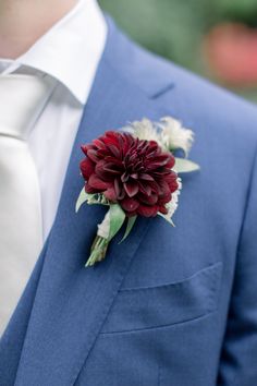 a man in a blue suit with a red flower on his lapel