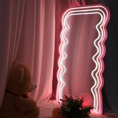 a teddy bear sitting in front of a mirror with lights on it's sides