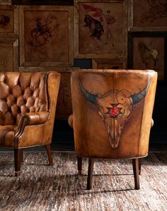 two leather chairs sitting next to each other in front of pictures on the wall behind them