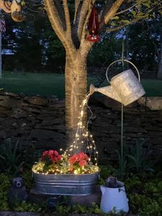 a potted tree with some lights on it and a watering can in the middle