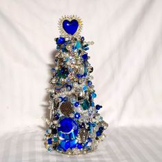 a blue and white christmas tree made out of glass beads, pearls, and other items