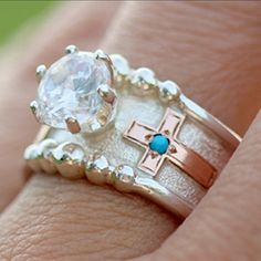 a close up of a person's hand wearing a ring with a cross on it