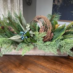 an arrangement of greenery in a basket on a table