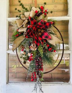 a wreath hanging on the side of a door with pine cones, berries and evergreens