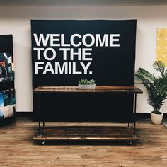 a welcome to the family sign in front of a black and white banner on a wall