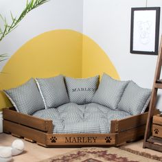 the dog bed is made out of wood and has black and white pillows on it