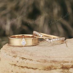 two gold wedding rings sitting on top of a rock next to each other with diamonds