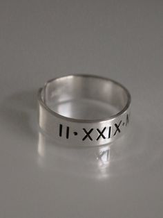 This Roman numeral ring is the perfect piece of personalized jewelry for anniversaries, promise rings and more. Crafted from quality materials, this date ring can be inscribed with custom Roman numerals for a unique piece of jewelry. A great gift for your loved one to commemorate a special occasion. Product Details: Materials: Aluminum, Sterling Silver, Fine Silver, 14k Gold Filled Color: Silver, Gold, Rose Gold Size: 6mm You will receive one hand-stamped ring filled with no enamel finish. Modern Engraved Ring With Round Band For Anniversary, Modern Engraved Round Band Ring For Anniversary, Minimalist Stamped Initial Ring For Anniversary, Modern Personalized Round Band Jewelry, Engraved Ring For Birthday, Personalized Silver Rings For Anniversary, Hand Stamped Round Band Jewelry For Anniversary, Classic Hand Stamped Rings For Anniversary, Modern Personalized Promise Rings