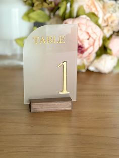 a table number on a wooden stand with flowers in the background