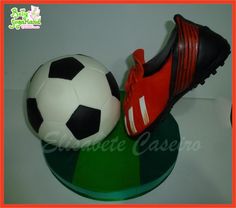 two soccer shoes and a ball sitting on top of a green base with an orange border