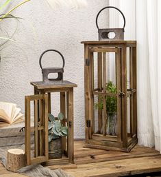 two wooden lanterns sitting next to each other on top of a wooden floor near a window