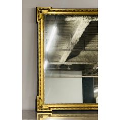 a large gold framed mirror hanging on the wall next to a white wall and floor