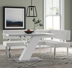 a white dining table and bench in a room with green walls, hardwood floors and rugs