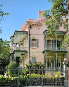 an old pink house with green shutters and balconies on the second story