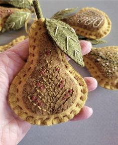 a hand holding a small piece of fruit with leaves on it's top and two other pieces in the background