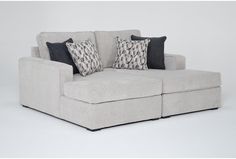 a couch with two pillows on it sitting in front of a white wall and floor