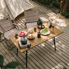 two chairs and a table with food on it in the middle of a wooden deck