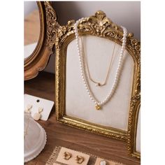 pearls and gold jewelry are displayed in front of a mirror on a wooden table with other items