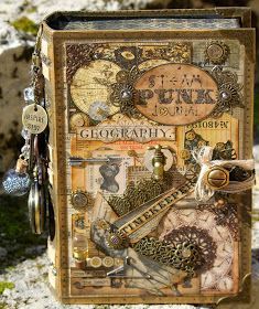 an altered book is sitting on top of some rocks and has charms hanging from it