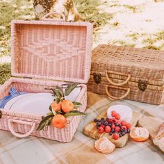 two wicker picnic baskets with plates and fruit in them on a plaid tablecloth