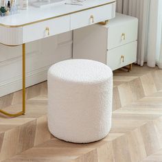 a white vanity with gold trim and drawers in a room next to a large window