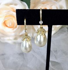 Best of both worlds! Iridescent pearls and clear cubic zirconia that capture the light from every angle with a perfectly translucent appeal come together to create a classy, sparkly and elegant pair of bridal earrings. The settings are gold / rhodium plated for a bright finish which enhances the intricate detailing and conveys a modern take on old elegance. Overall length of the earring is 1.5" (approx. 3.8cm). Width: 0.4" (approx. 1.2cm). Weight: 6g. Available in Yellow Gold and Silver with Whi White Pearl Bridal Earrings With Diamond Accents, Gold Pearl Earrings With Diamond Accents And Cubic Zirconia, Round Crystal Pearl Earrings For Party, White Pearl Jewelry With Sparkling Stones, White Pearl Earrings With Diamond Accents For Wedding, White Crystal Pearl Earrings For Formal Occasions, Classic Pearl Charm Jewelry For Party, Pearl Earrings With Sparkling Stones For Parties, Elegant Pearl Drop Jewelry