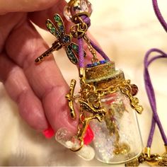 a hand holding a glass jar with a cross on it and some charms attached to it