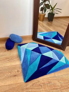 a mirror and blue rug on the floor in front of a wooden floor with a potted plant next to it