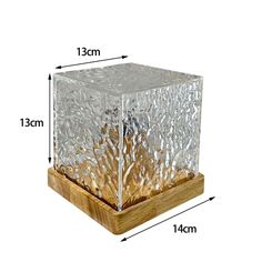 a glass block sitting on top of a wooden stand next to a white wall with measurements