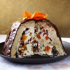 a chocolate cake on a black plate with an orange bow around the edge, sitting on a white tablecloth